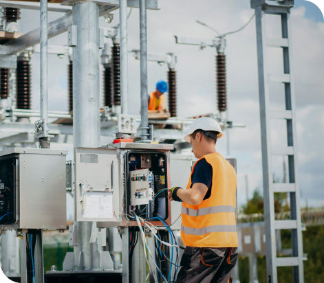 un lavoratore con gillet arancione catarifrangente e caschetto bianco che controlla i cavi di un contatore